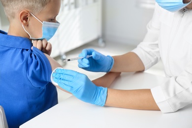 Photo of Doctor vaccinating little boy in hospital. Health care