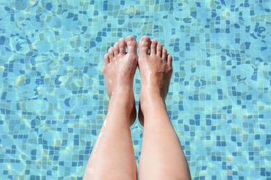 Photo of Woman holding feet over water in swimming pool, closeup