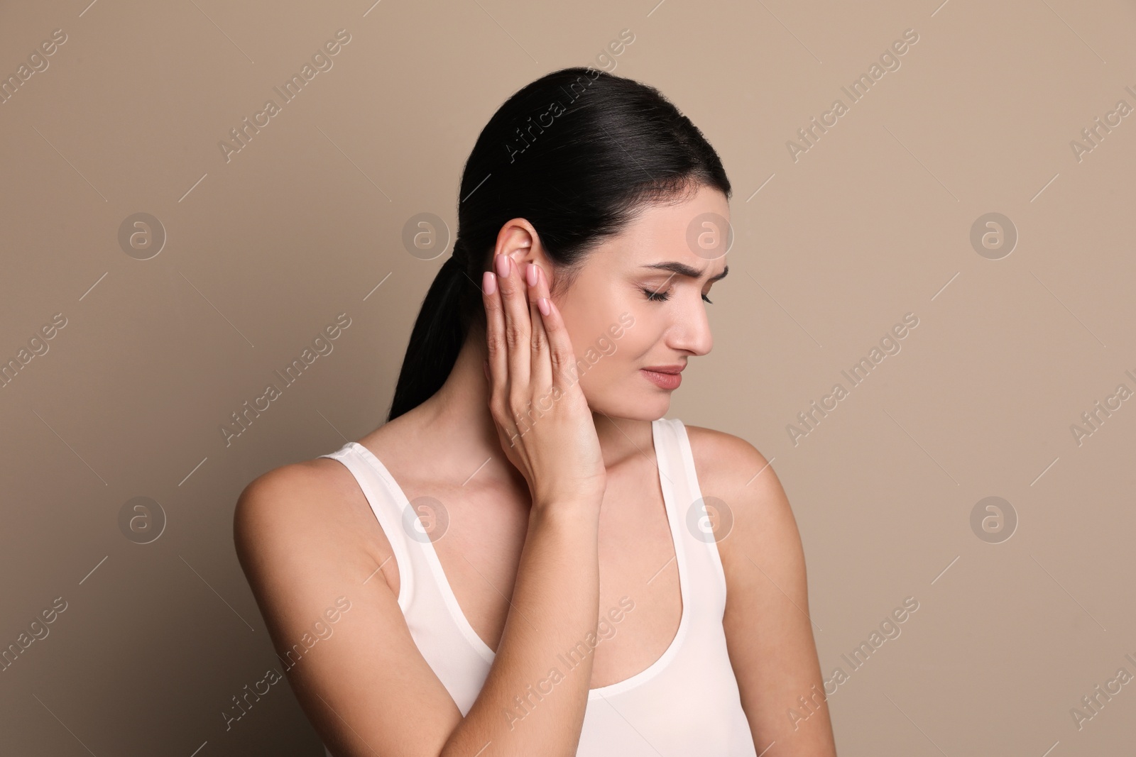 Photo of Young woman suffering from ear pain on grey background