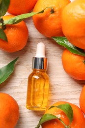 Photo of Bottle of tangerine essential oil and fresh fruits on white wooden table, flat lay