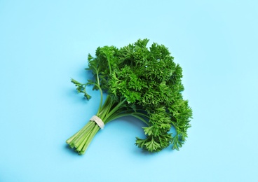 Photo of Bunch of fresh green parsley on blue background