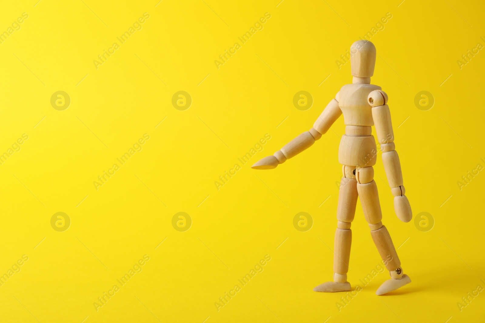 Photo of Wooden human model on yellow background, space for text. Mini mannequin