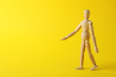 Photo of Wooden human model on yellow background, space for text. Mini mannequin