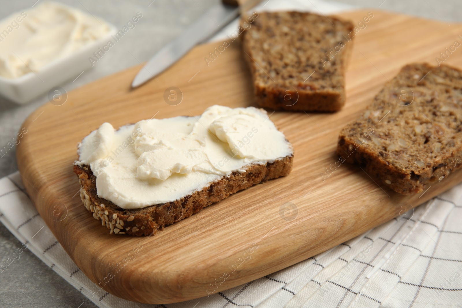 Photo of Bread with cream cheese on wooden table, closeup