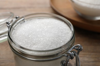 Photo of Granulated sugar in glass jar on table, closeup