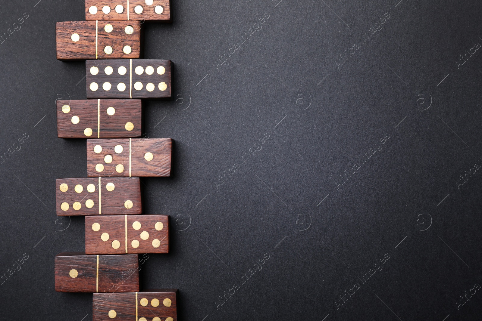 Photo of Wooden domino tiles on black background, flat lay. Space for text