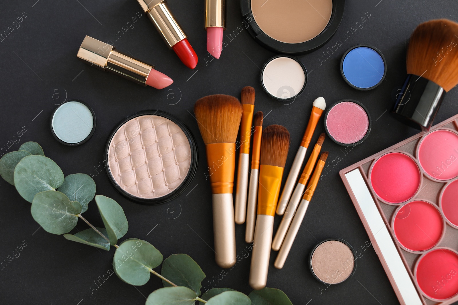 Photo of Flat lay composition with makeup brushes and cosmetic products on black background