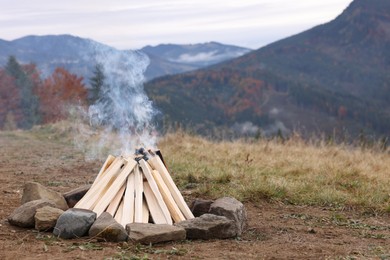 Photo of Bonfire with smoldering firewood in mountains. Camping season