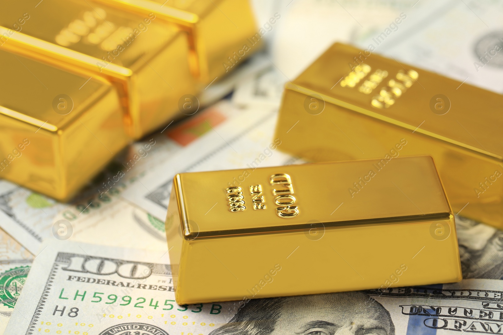 Photo of Shiny gold bars on dollar banknotes, closeup