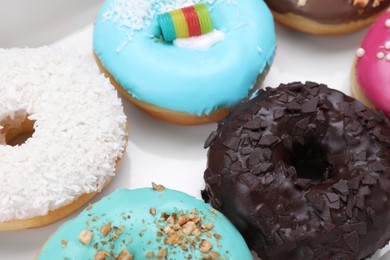 Photo of Different tasty glazed donuts in box, closeup