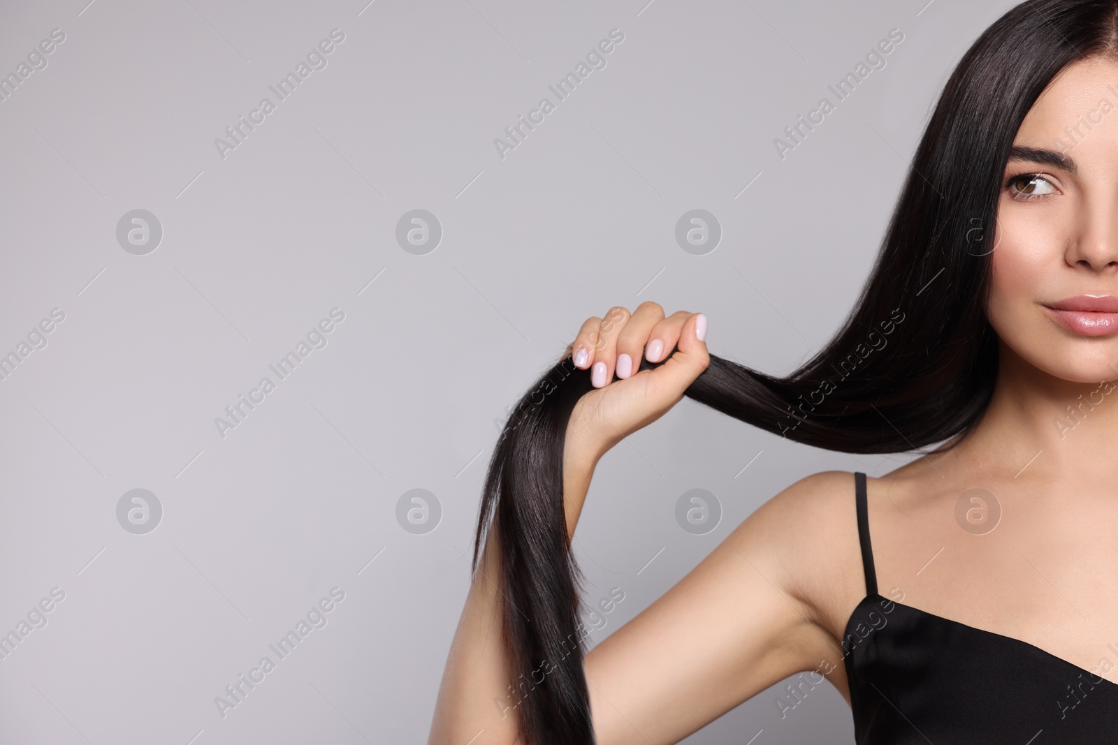Photo of Portrait of beautiful young woman with healthy strong hair on light grey background, closeup. Space for text