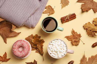 Flat lay composition with hot cozy drinks and autumn leaves on color background