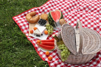 Photo of Picnic blanket with delicious food and wine outdoors on summer day