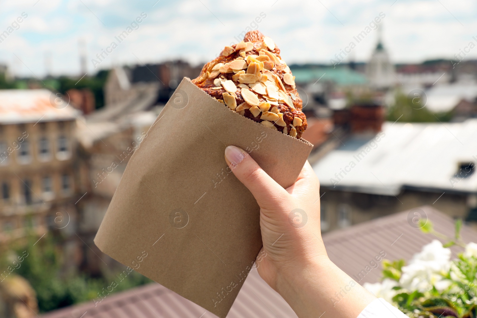 Photo of Woman with delicious croissant outdoors, closeup view