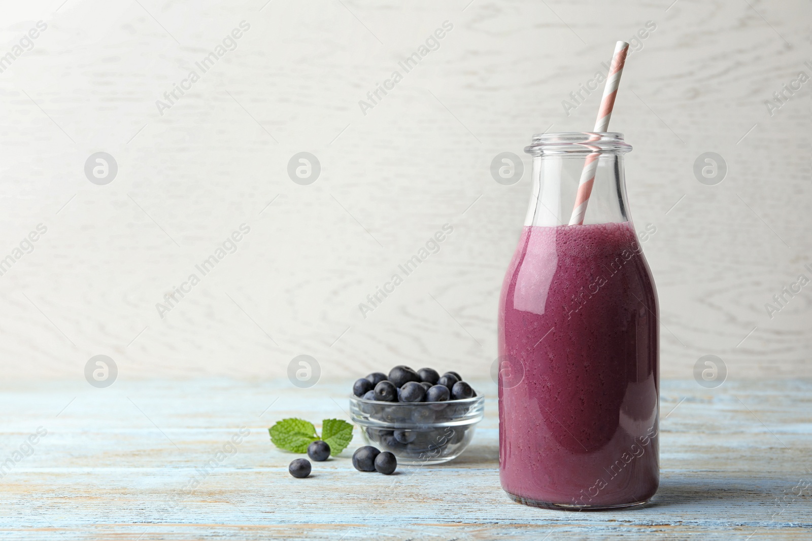 Photo of Fresh acai drink with berries on wooden table against light background. Space for text