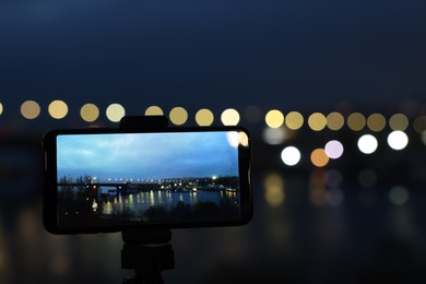 Photo of Taking photo with smartphone on tripod near river at night