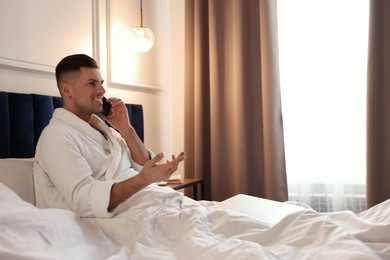 Photo of Handsome man talking on phone in hotel room