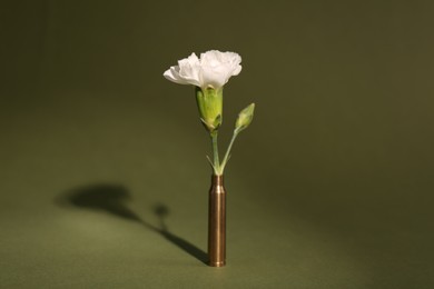 Bullet cartridge case and beautiful carnation flower on dark green background