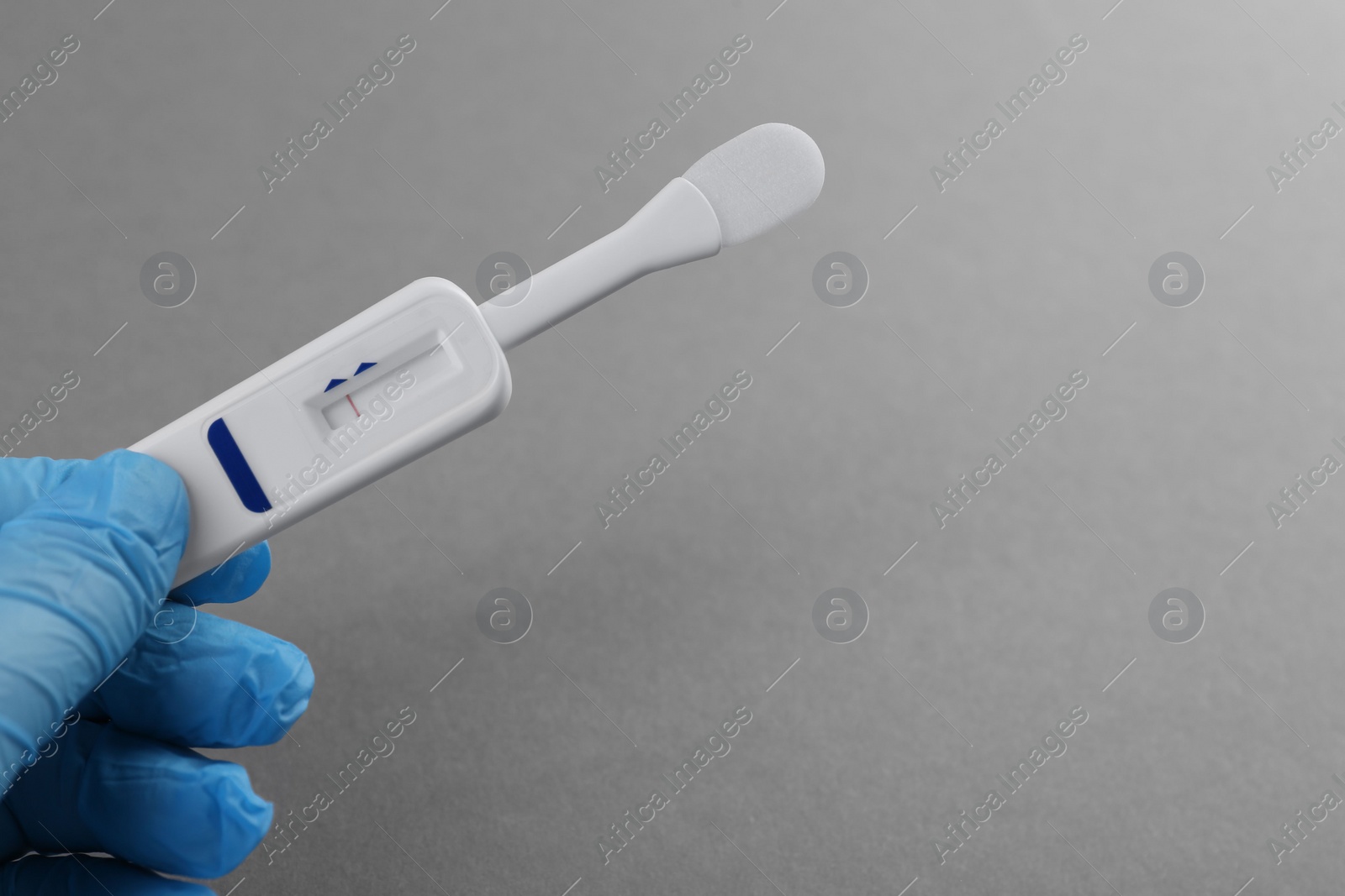 Photo of Doctor holding disposable express test on light grey background, closeup. Space for text