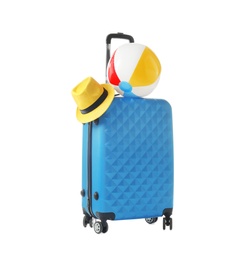 Photo of Blue suitcase with hat and inflatable ball packed for journey on white background