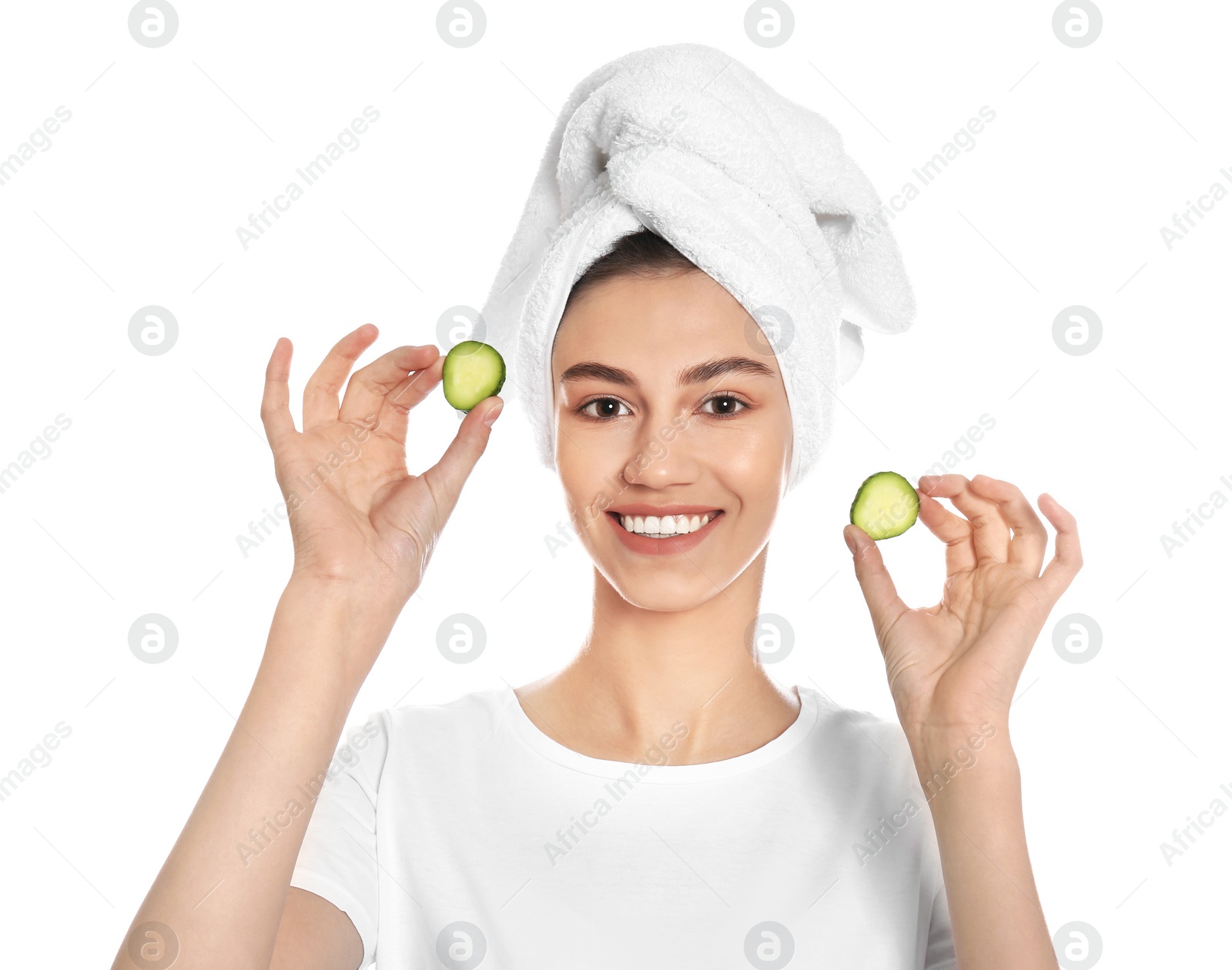 Photo of Happy young woman with towel holding cucumber slices on white background. Organic face mask