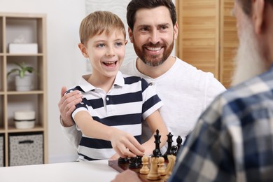 Photo of Family playing chess together at table in room