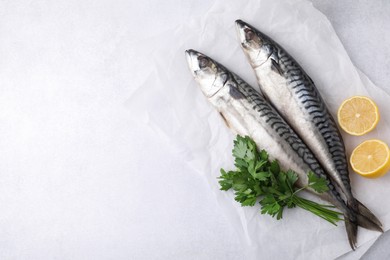 Photo of Tasty salted mackerels, parsley and cut lemons on light table, top view. Space for text