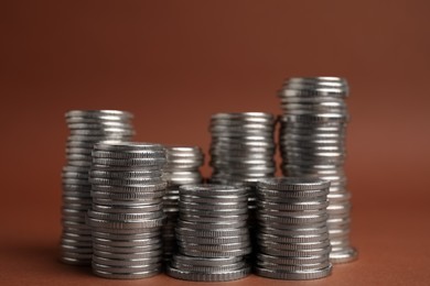 Photo of Many silver coins stacked on brown background