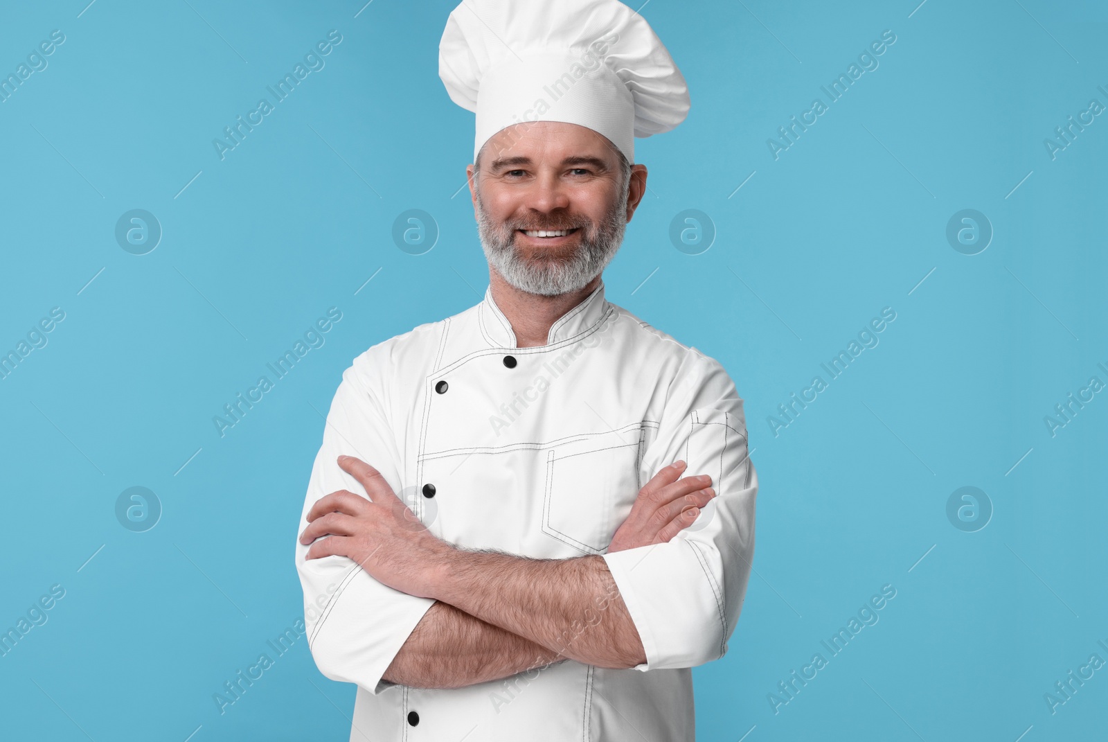 Photo of Happy chef in uniform on light blue background