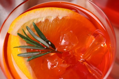 Aperol spritz cocktail, ice cubes, rosemary and orange slices in glass, closeup