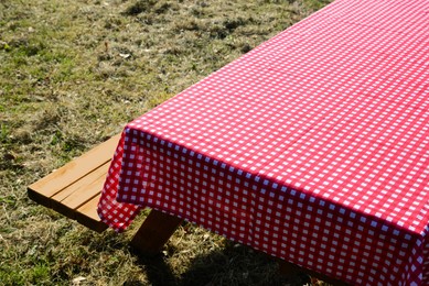 Photo of Empty picnic table with red and white checkered tablecloth in park on sunny day