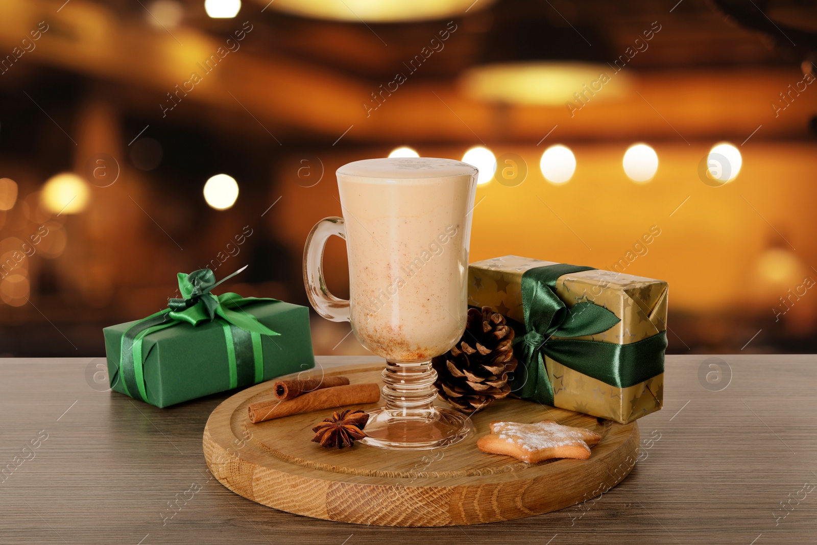 Image of Glass of delicious eggnog, spices, cookie and gift boxes on wooden table in bar