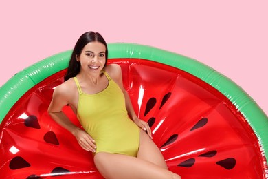 Photo of Young woman wearing stylish swimsuit on inflatable mattress against pink background