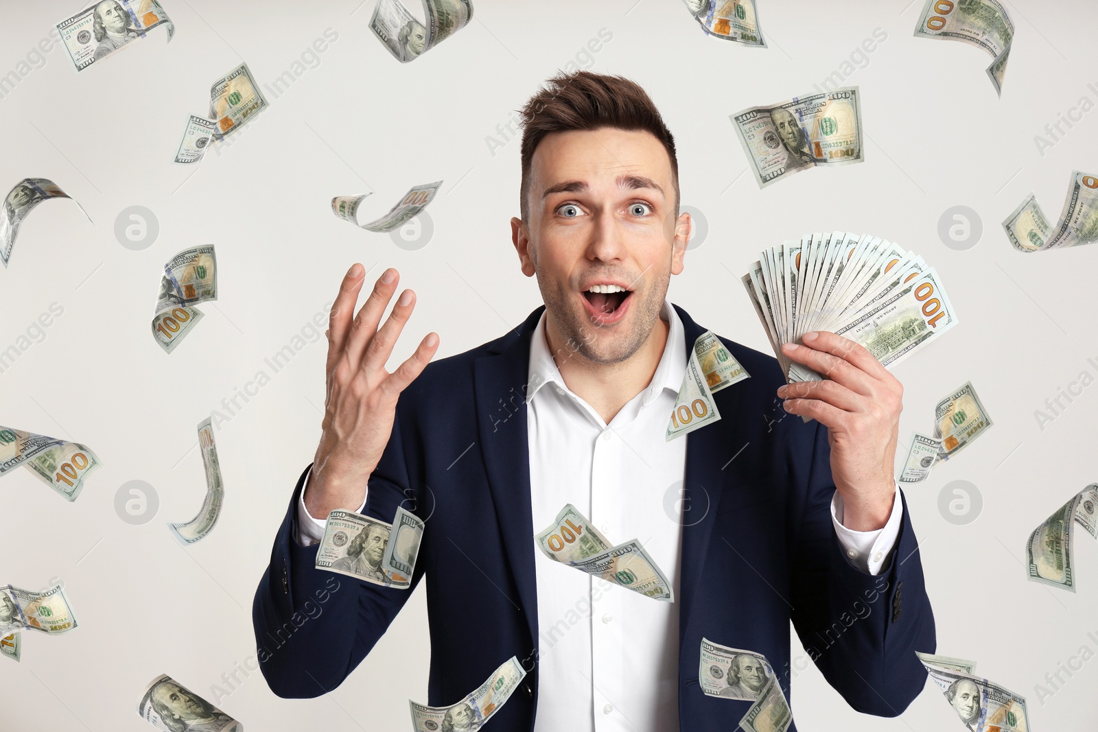 Image of Man with American dollars under money rain on light grey background