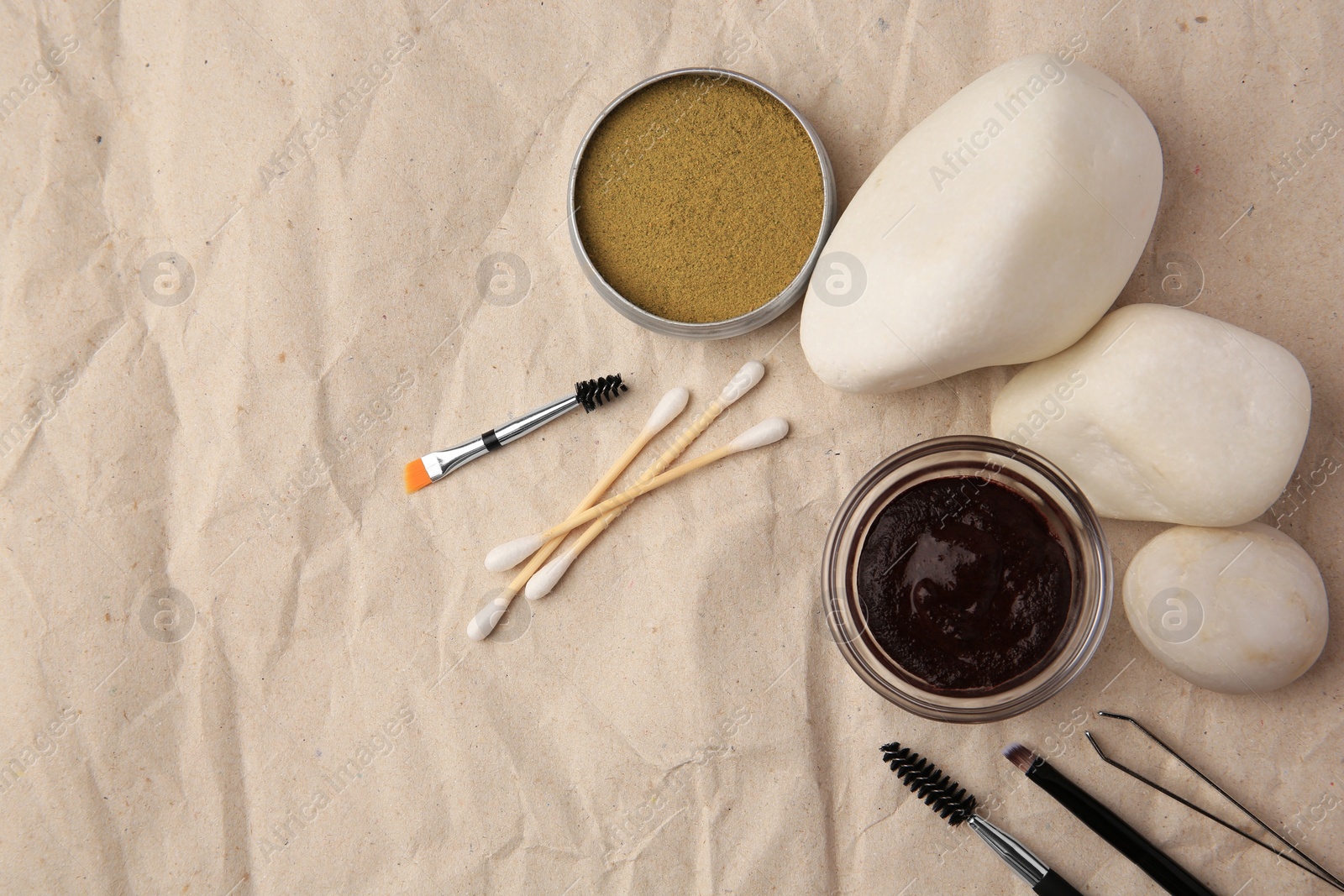 Photo of Flat lay composition with eyebrow henna and tools on crumpled paper. Space for text