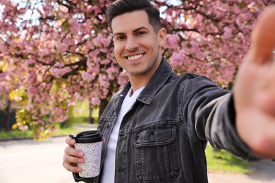 Photo of Happy man taking selfie with coffee outdoors on spring day