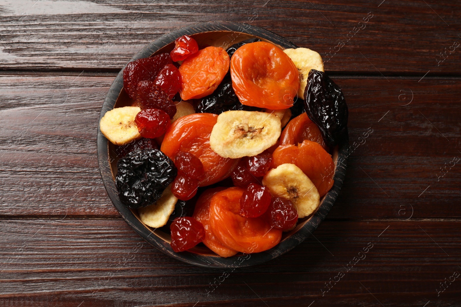 Photo of Mix of delicious dried fruits on wooden table, top view