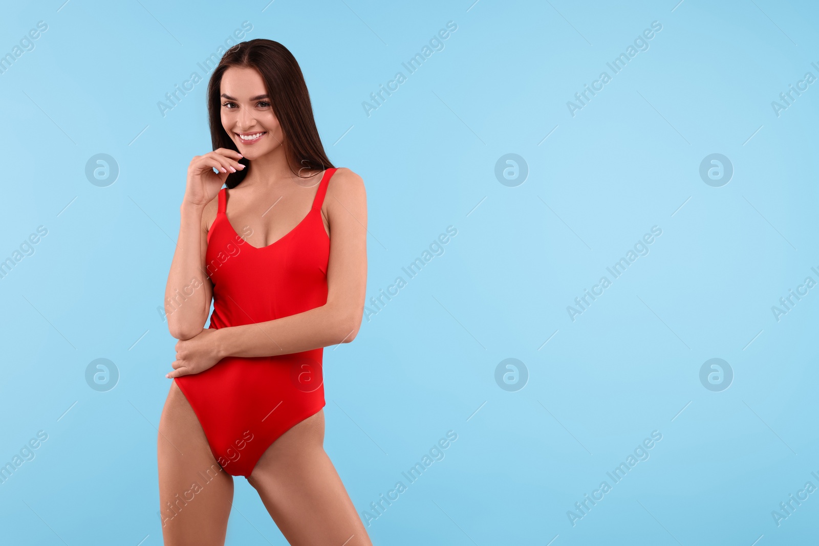 Photo of Young woman in stylish swimsuit on light blue background, space for text