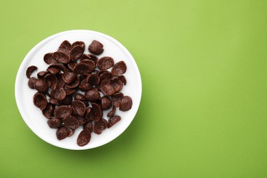 Photo of Breakfast cereal. Chocolate corn flakes and milk in bowl on light green background, top view. Space for text