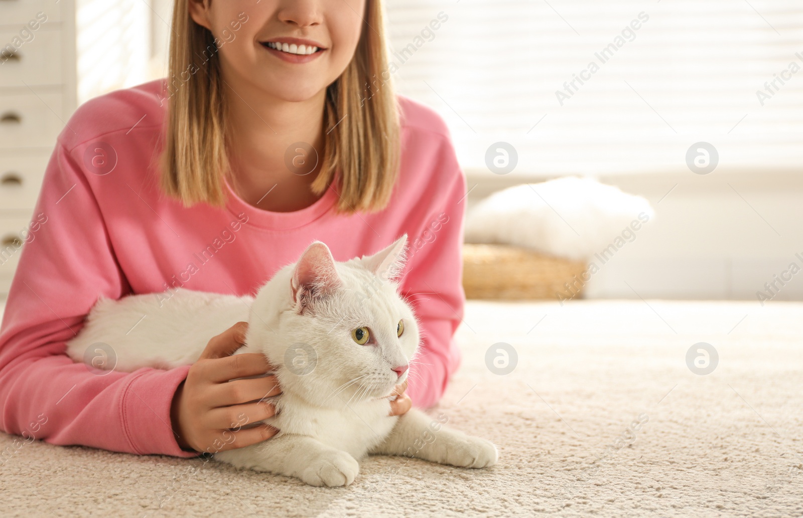 Photo of Young woman with her beautiful white cat at home, space for text. Fluffy pet