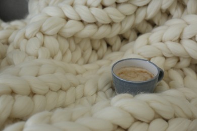 Photo of Cup of coffee on white knitted plaid. Space for text