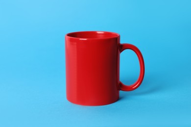 Photo of One red ceramic mug on light blue background