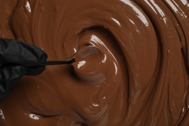 Person making tasty milk chocolate paste, top view