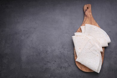 Photo of Delicious folded Armenian lavash on dark table, top view. Space for text