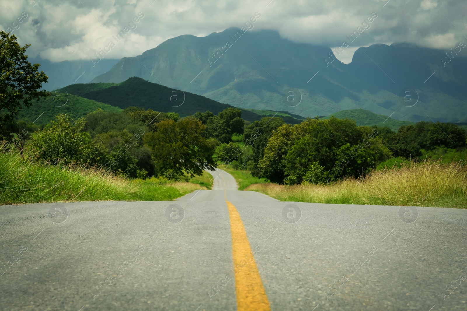 Photo of Picturesque view of empty road near trees and mountains