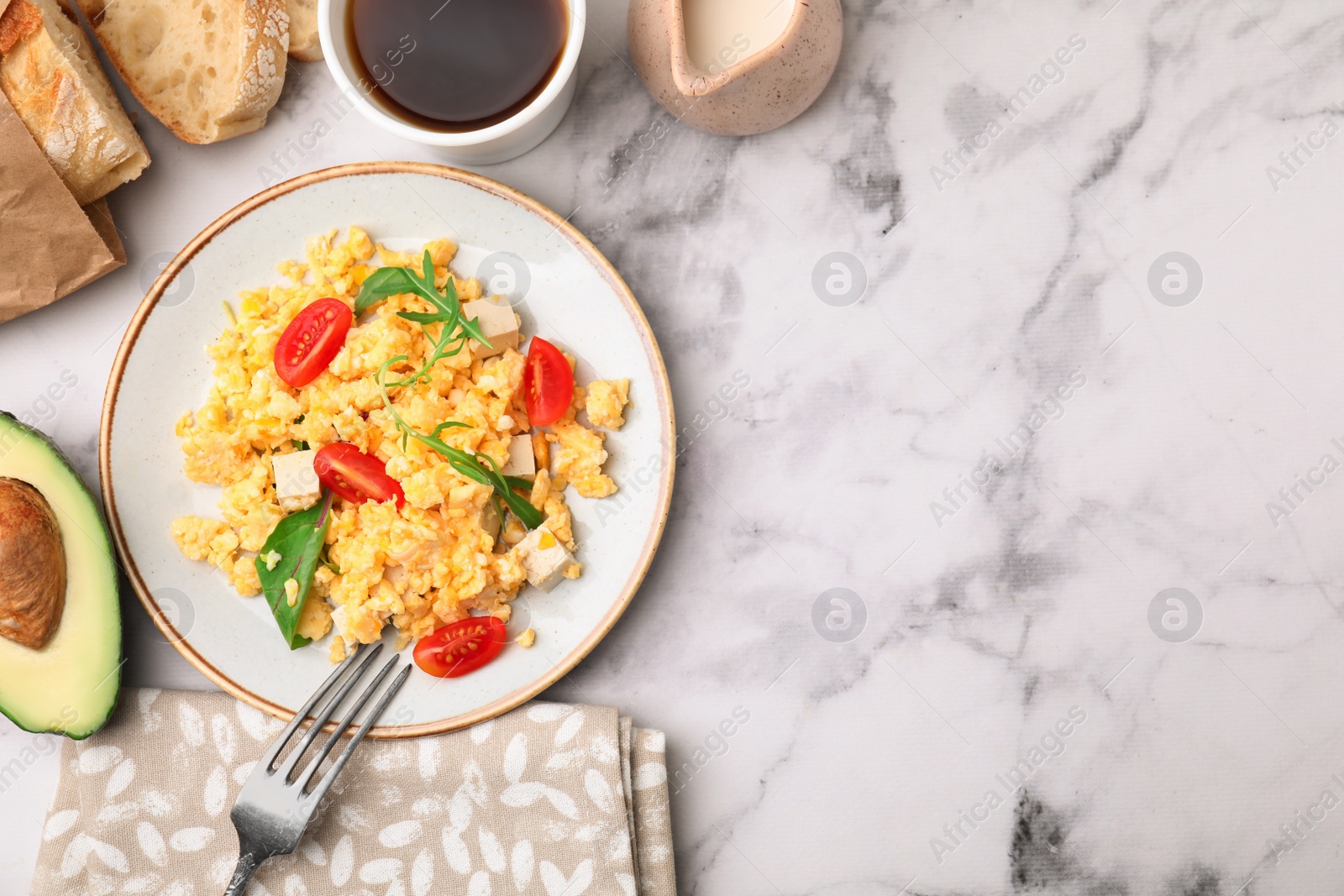 Photo of Delicious scrambled eggs, tofu and tomatoes served on white marble table, flat lay. Space for text