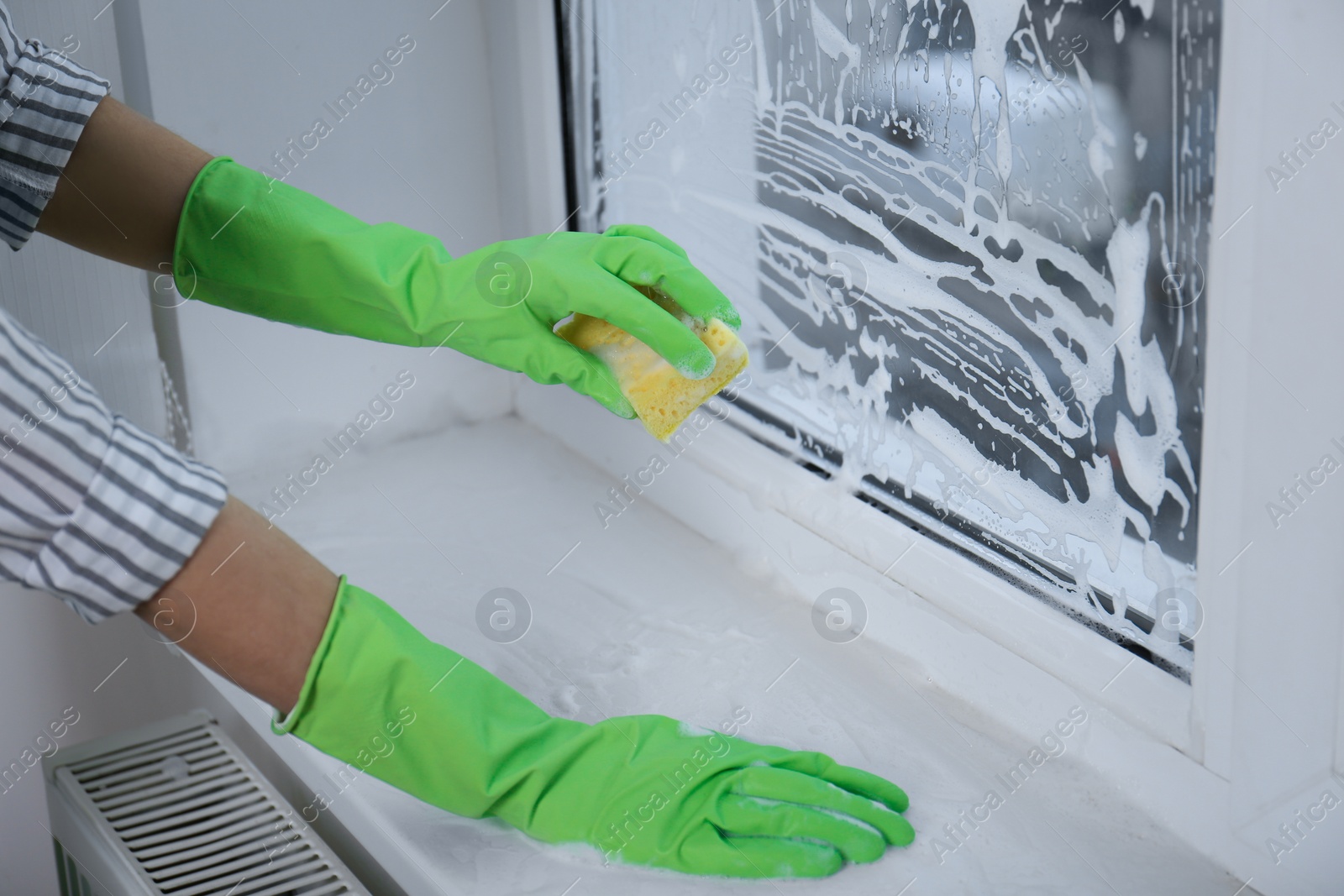 Photo of Woman cleaning window with sponge indoors, closeup