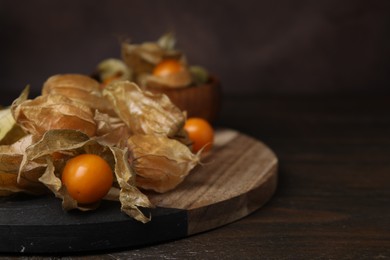 Photo of Ripe physalis fruits with calyxes on wooden table, closeup. Space for text