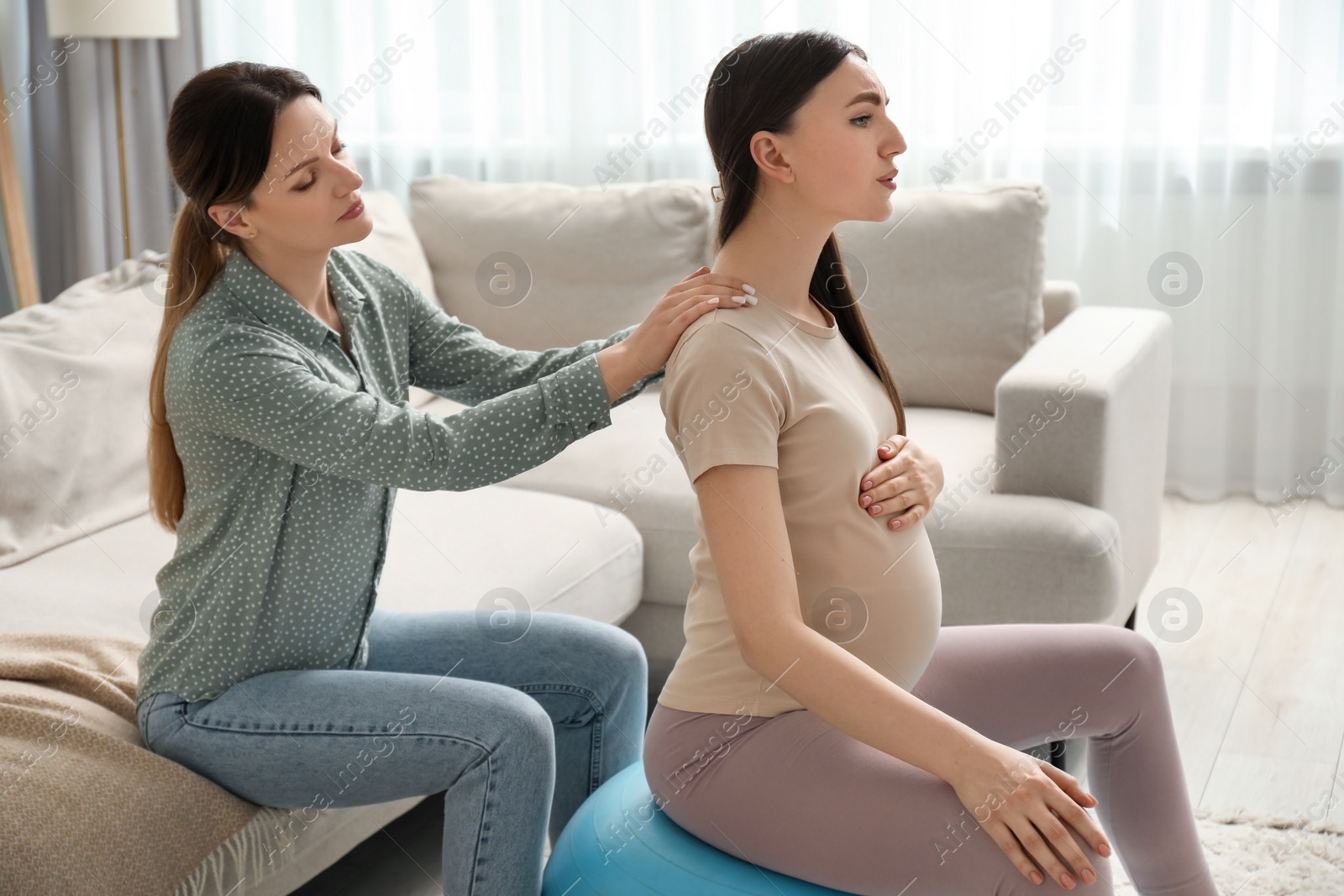 Photo of Doula massaging pregnant woman at home. Preparation for child birth