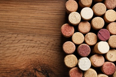 Photo of Flat lay composition with many corks of wine bottles on wooden table. Space for text